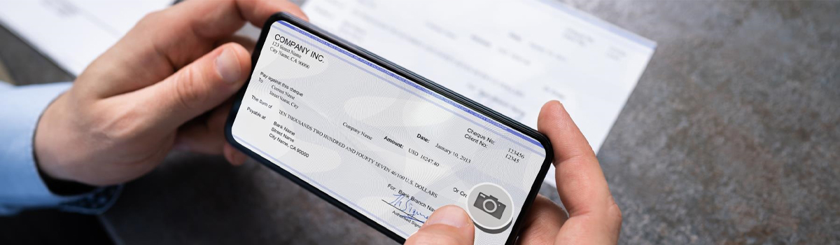 person holding checkbook with mobile deposit camera icon