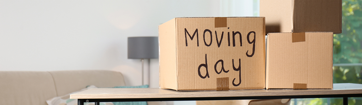 Boxes on table in new home being unpacked. One box has moving day written on it.