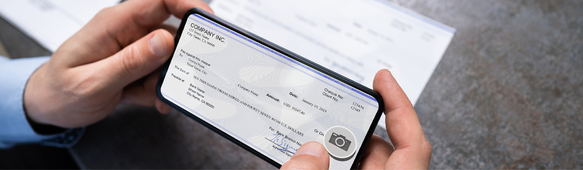 Hands holding checkbook showing checks with camera icon for mobile deposit