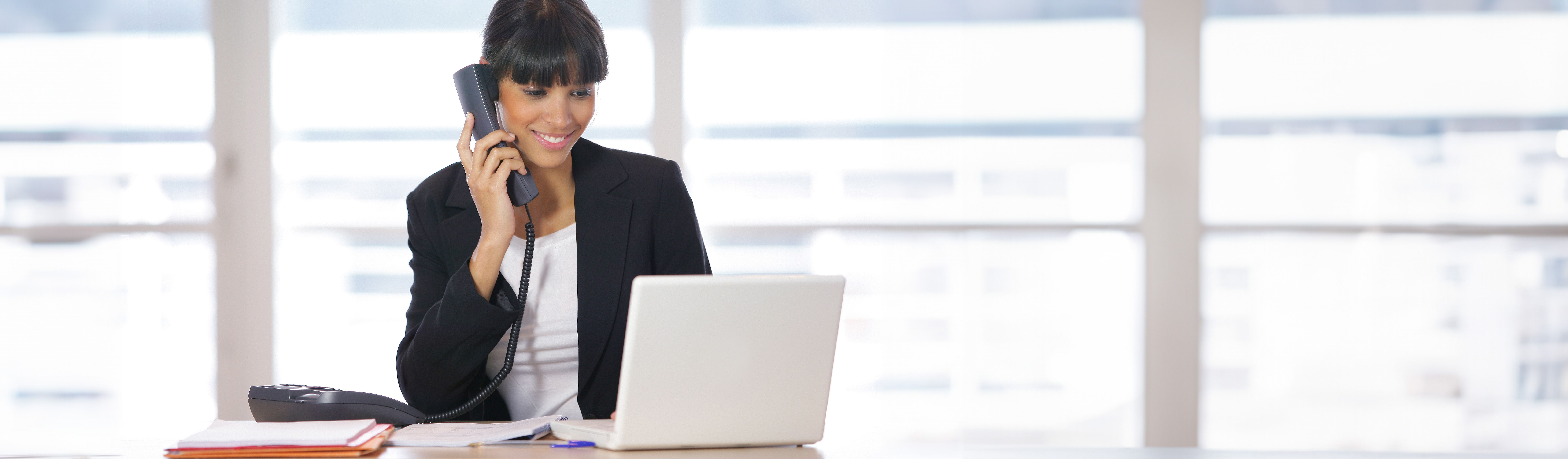 Business woman talking on phone at work computer
