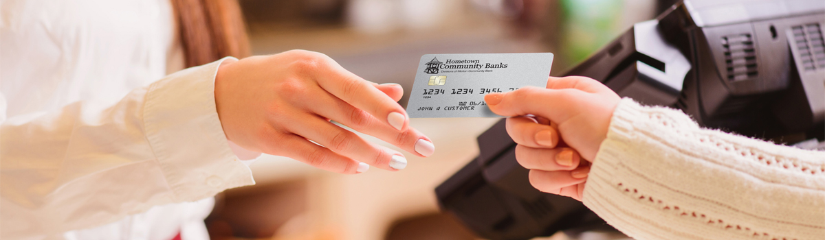 Close up of customer handing Hometown Banks Credit card to cashier 