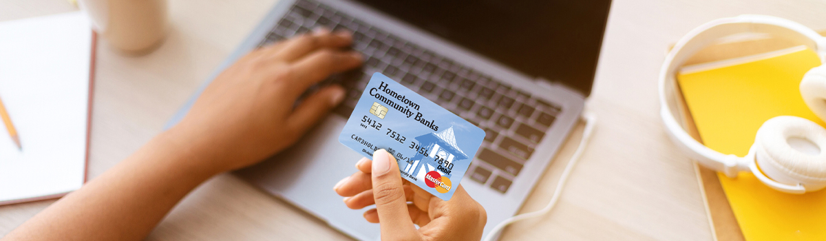 Close up of Hometown Banks Debit Card being used for an online purchase with a laptop