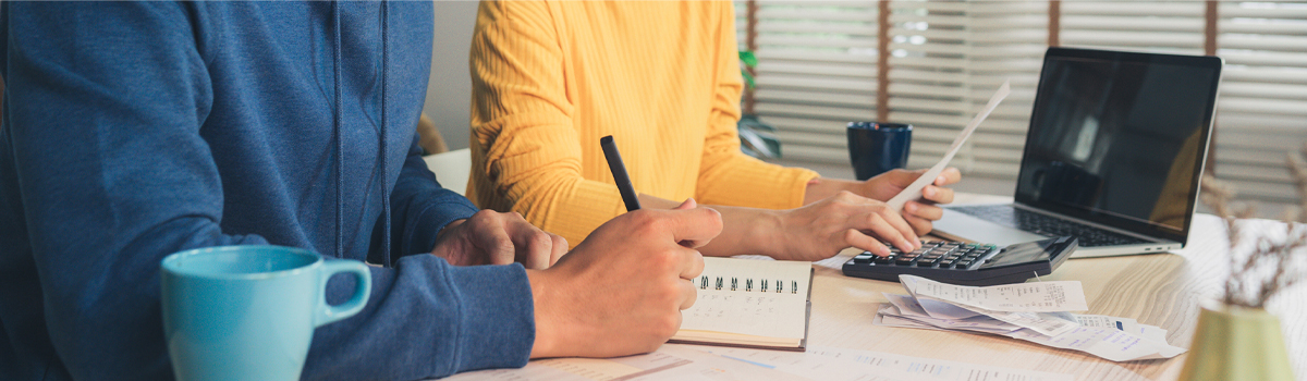 Man and woman at desk with notepad laptop and calculator